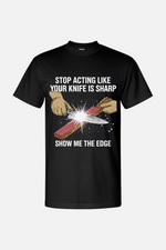 Black t-shirt featuring a white graphic of hands sharpening a knife on a stone with spark effects, with the text “Stop Acting Like Your Knife Is Sharp” above and “Show Me the Edge” below.