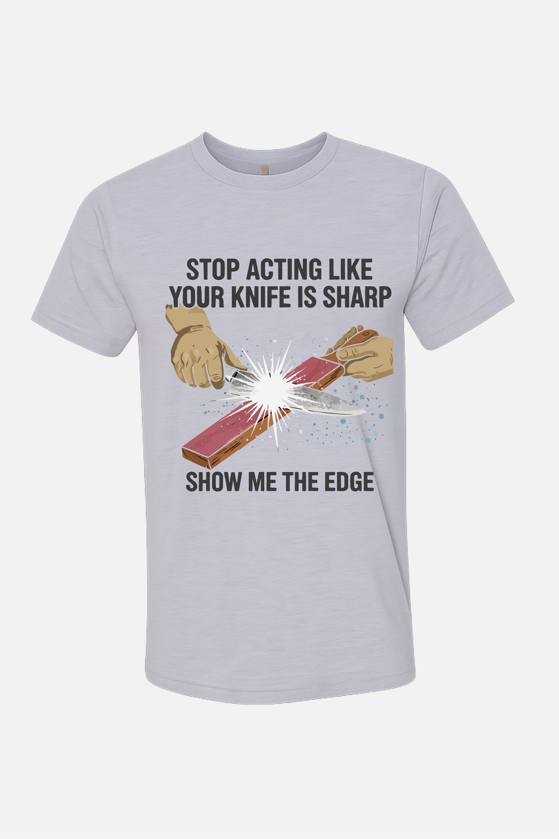 White t-shirt featuring a graphic of hands sharpening a knife on a stone with spark effects, with the text “Stop Acting Like Your Knife Is Sharp” above and “Show Me the Edge” below.